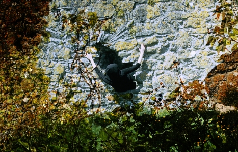 EL Putnam crawls out of a hole in a castle wall