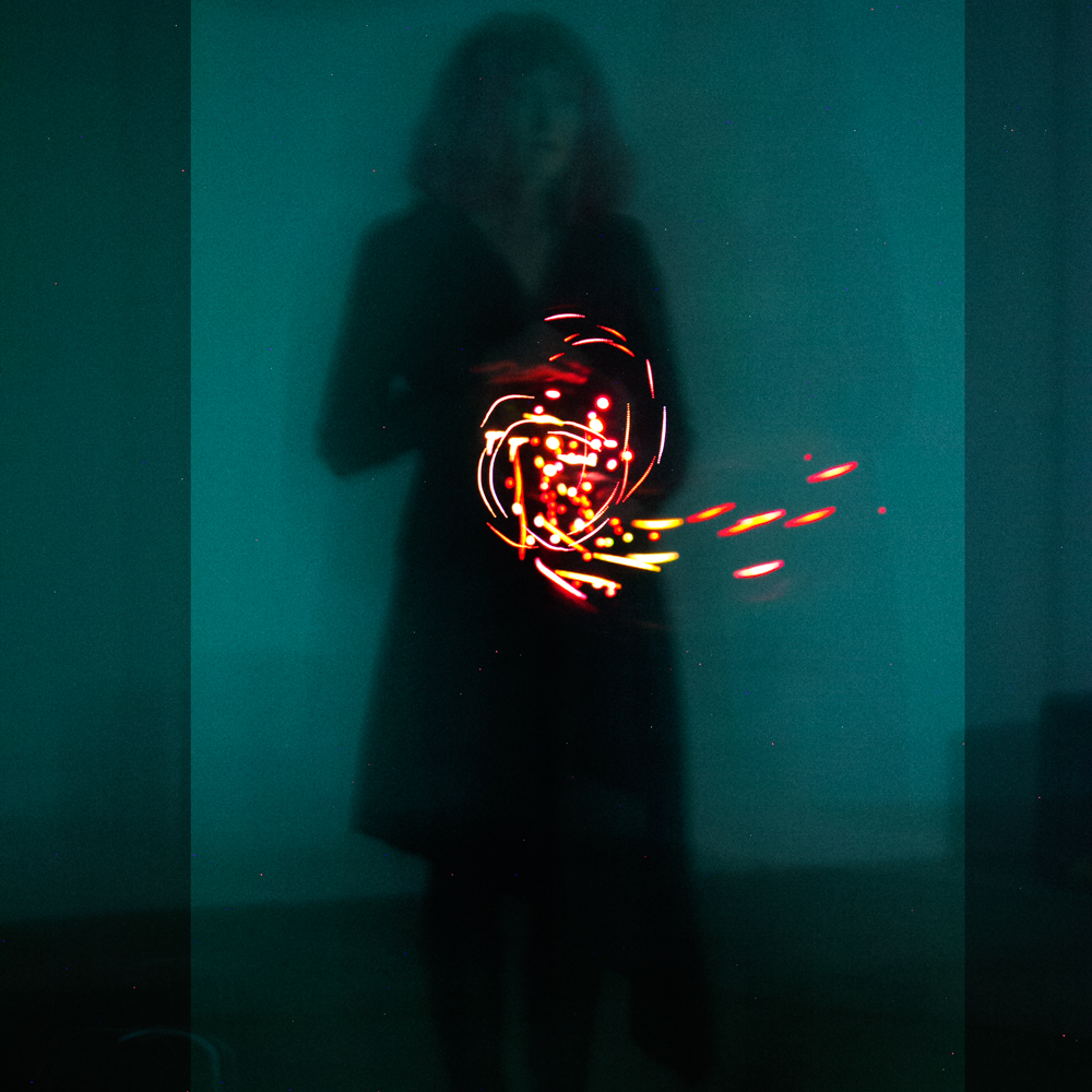 Swirl of magenta lights over silhouetted body with teal background