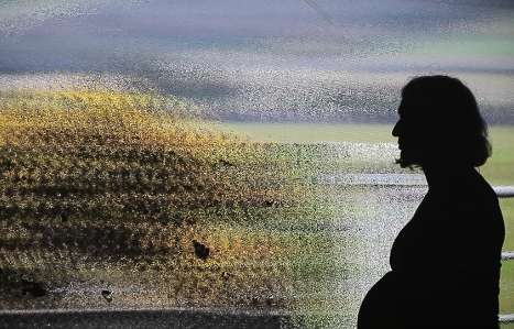 A side silhouette of a pregnant woman  in front of a glitched landscape