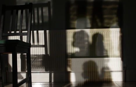 Repeating shadows of woman holding baby and chair in a kitchen